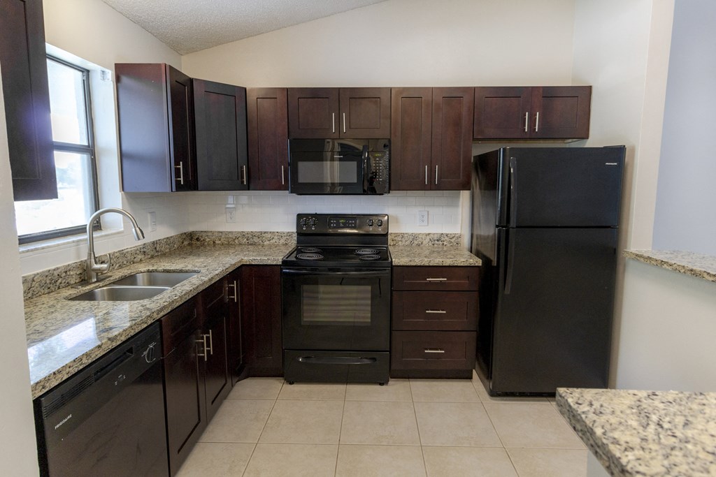 A kitchen with black appliances and brown cabinets.